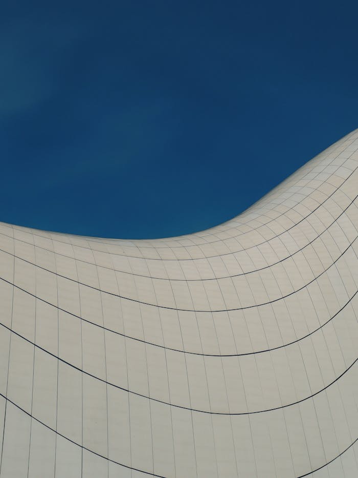 Modern architectural structure with curved lines and blue sky background capturing innovation in design.